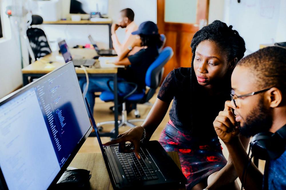 Two students coding on a laptop